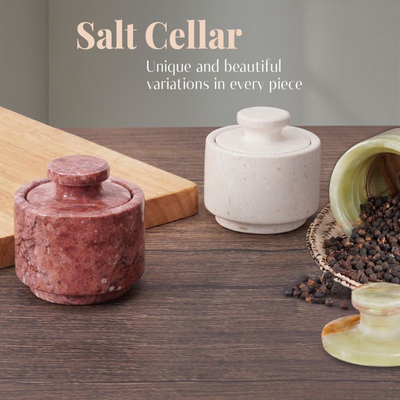 Display of red, white and green onyx salt cellars with black pepper on wood table