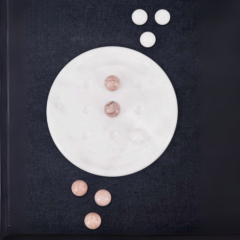 Top view of marinara and white marble Tic Tac Toe game on dark fabric