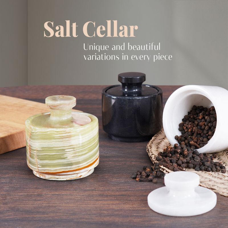 Green, black, and white marble salt cellars on wood table
