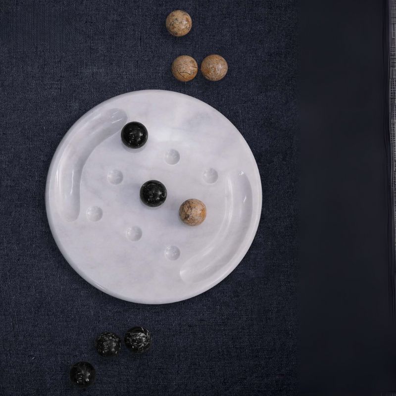 Tic Tac Toe marble board game set with scattered balls on dark surface