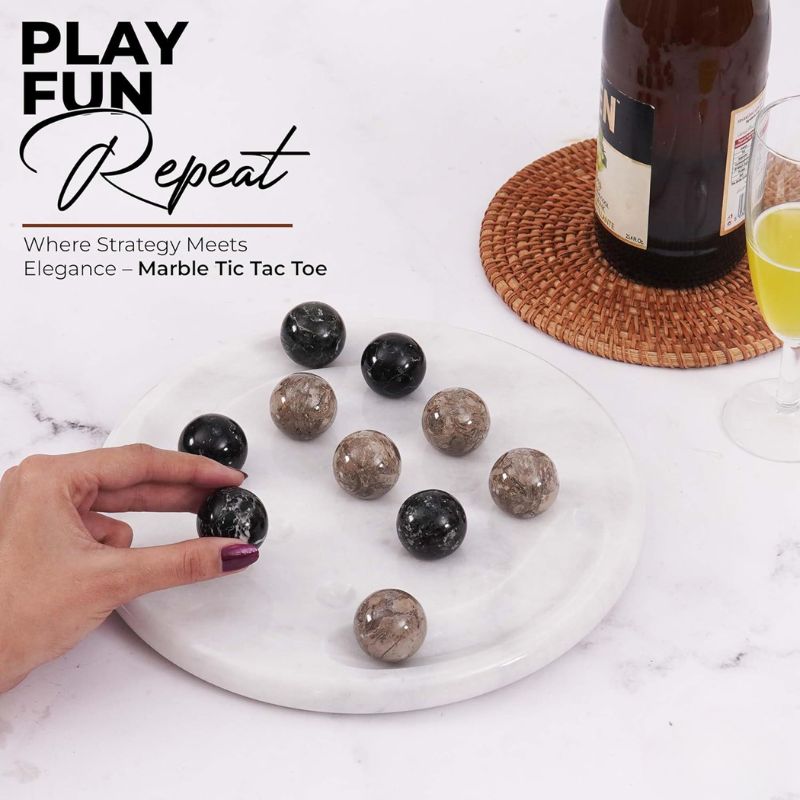 Hand playing with oceanic marble Tic Tac Toe game set on table