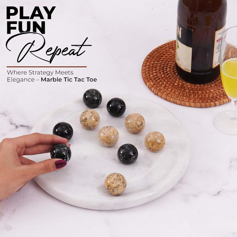 Hand playing marble Tic Tac Toe game set with drink on side