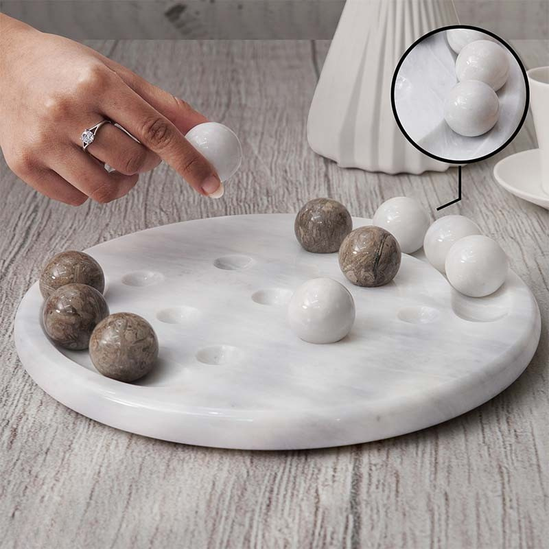 Zoomed marble Tic Tac Toe set with oceanic and white playing balls, shown in a home entertainment setting.
