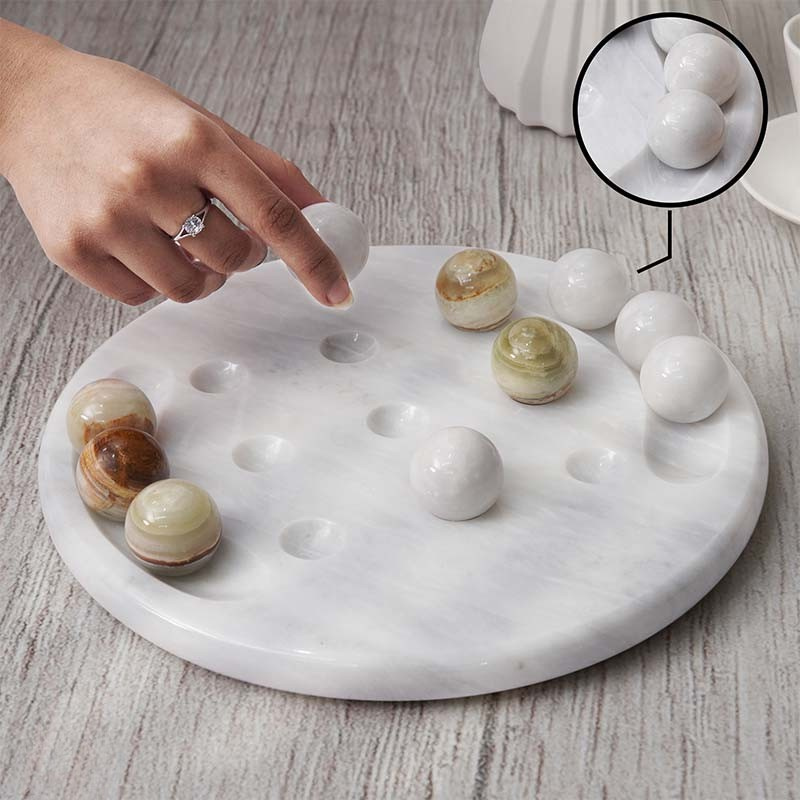 Person playing on green and white marble Tic Tac Toe board set, suitable for tabletop game nights.