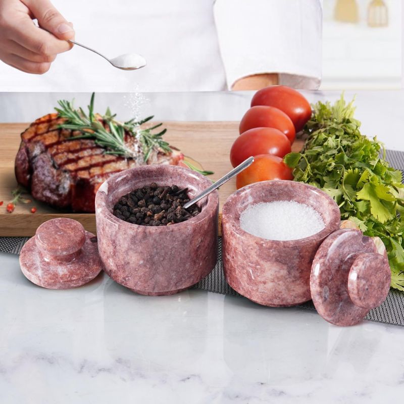 Red marble salt cellar jars used for pepper and salt beside steak meal