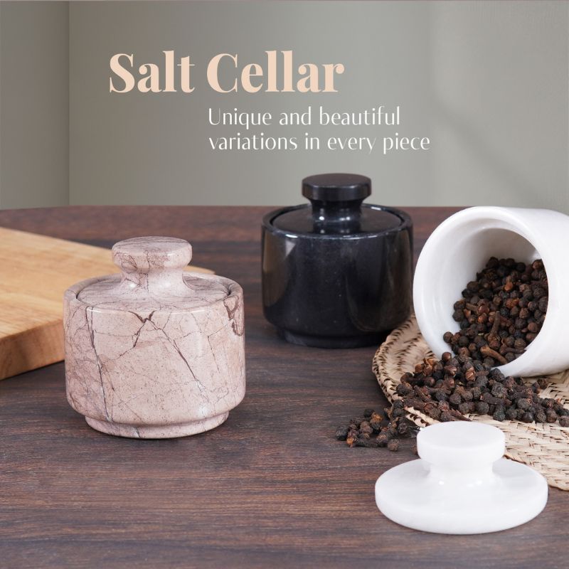Collection of marble salt cellars on a wooden surface with pepper