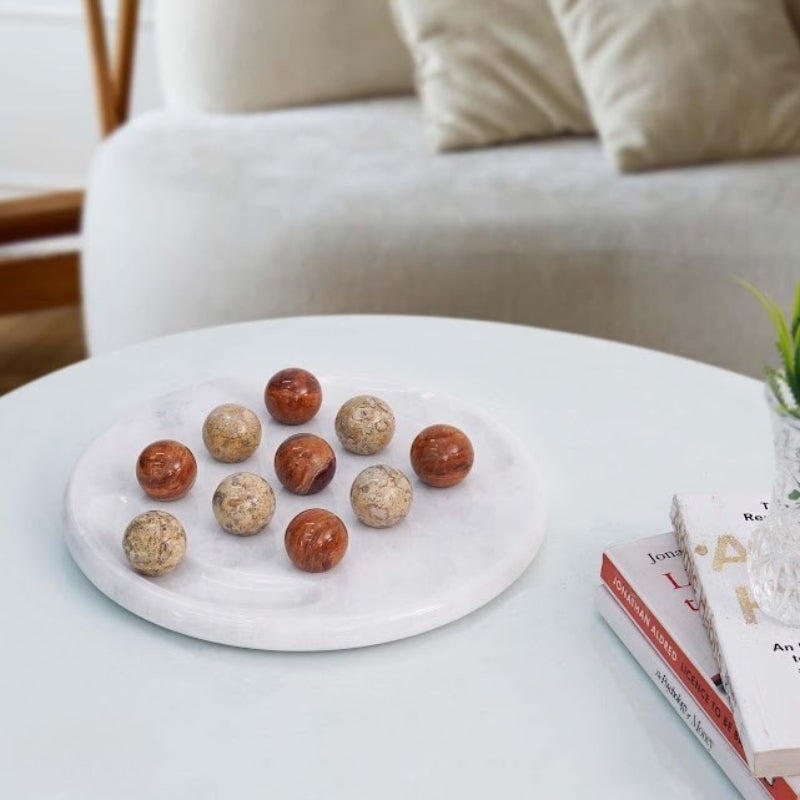 Tic Tac Toe game set with red and coral marble balls placed on modern coffee table