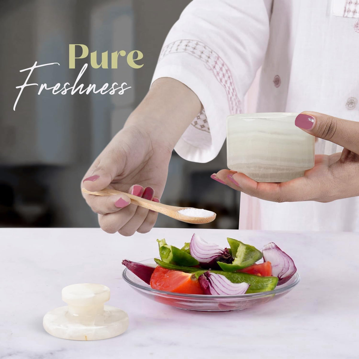 Woman using white onyx marble salt cellar to season fresh salad